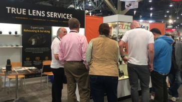 Group of people crowding around the True Lens Services booth 